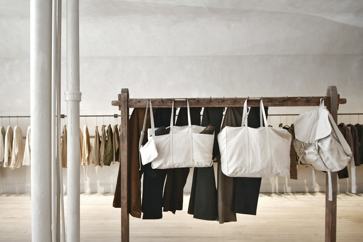 Minimalist retail display with canvas bags and clothing racks.
