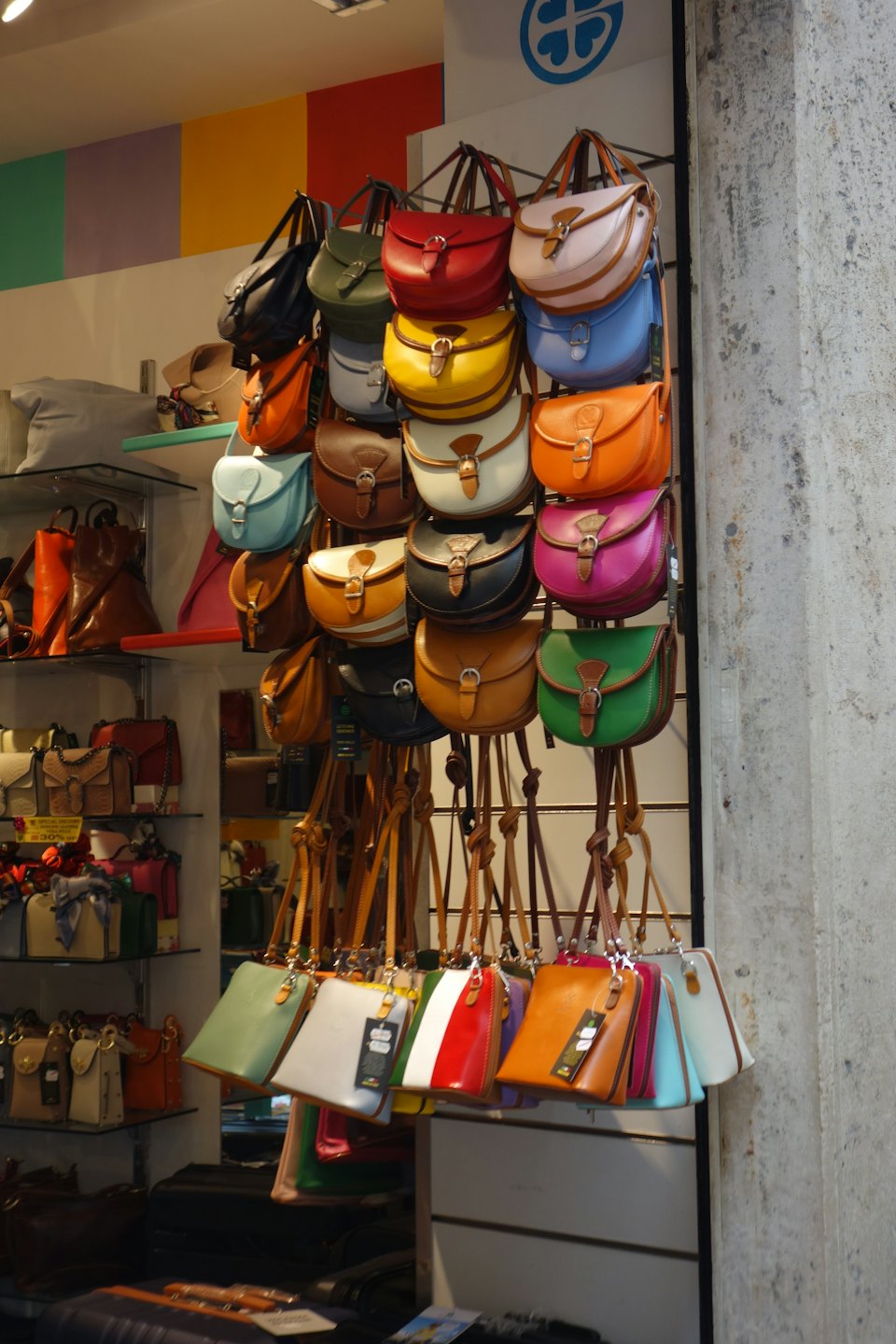 Leather handbags hang on display racks inside a retail store.
